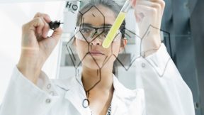 Medizinstudierende zeichnet im Labor Atome auf eine Glaswand.